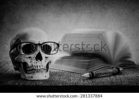 Still life with skull, old book and pencil on wooden table over grunge background, black and white