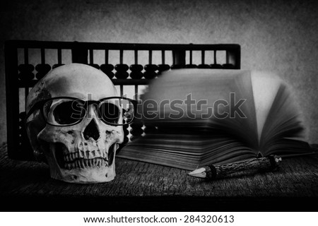 Still life with skull, old book,abacus and pencil on wooden table over grunge background, black and white