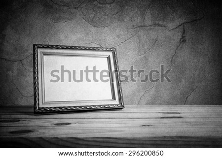 Vintage photo frame on wooden table over grunge background, Still life style, black and white