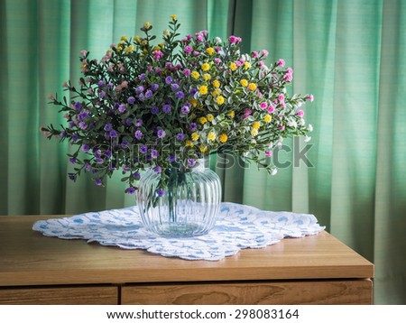 Bouquet of flowers on a wooden table over green curtain background in the bedroom