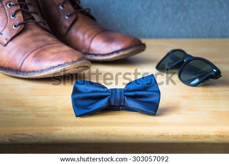 Men\'s casual, bow tie with sunglasses and shoes on wooden over wall grunge background