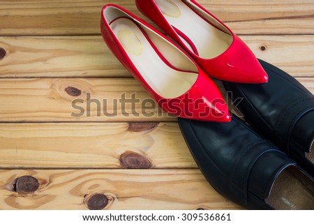 Black men shoes and red women shoes on wooden table background
