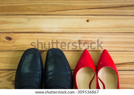 Black men shoes and red women shoes on wooden table background