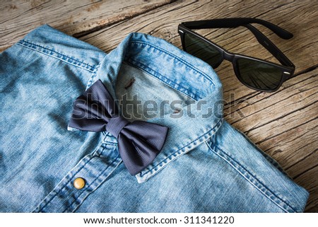 Men\'s casual outfits with jeans shirt, bow tie and sunglasses on wooden background