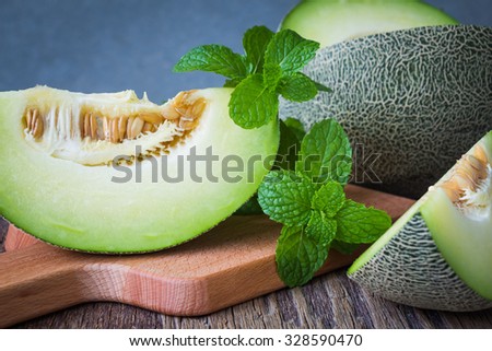 Fresh green melons sliced on wooden table over grunge background