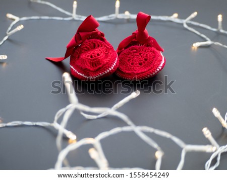 Baby red shoes on a dark grey background decorated with fairy lights. Christmas winter theme. New baby announcement concept. Baby shower invitation. Baptism invitation idea. Flat lay top view. Zdjęcia stock © 