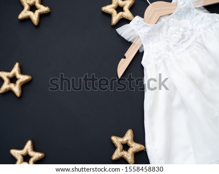 Baby girl white dress on a dark grey background decorated with golden stars.  Baptism invitation idea. Christmas winter theme. New baby announcement concept. Baby shower invitation. Flat lay top view. Zdjęcia stock © 