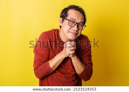 Casual man in glasses with pleading facial expression, pleading with tightly holding palms isolated on yellow background Imagine de stoc © 