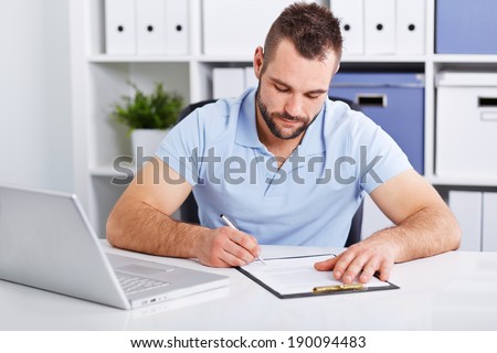 Young businessman in blue polo shirt signs a contract on white table