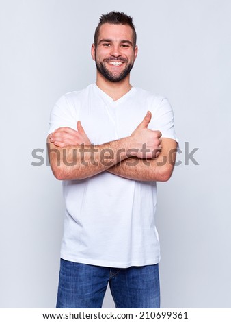 Young handsome man in a white t-shirt on gray background