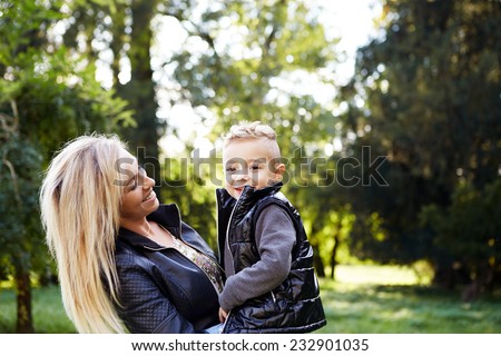 Mother holding son in the park and laughing together