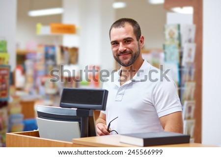 Young salesman at the checkout in a bookstore