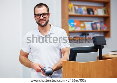 Young salesman at the checkout in a bookstore