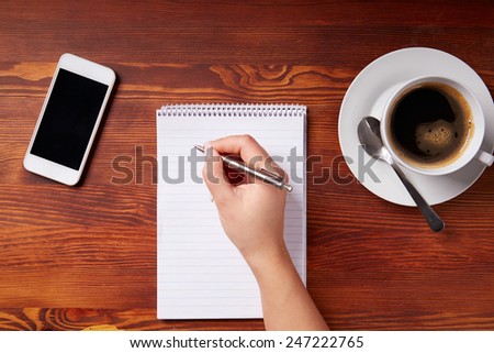 Woman hand writing in a notepad, top view