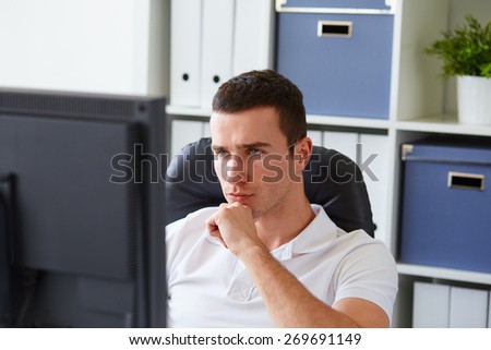 Young man sitting behind the monitor in the office