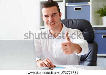 Businessman working on laptop and making the ok gesture