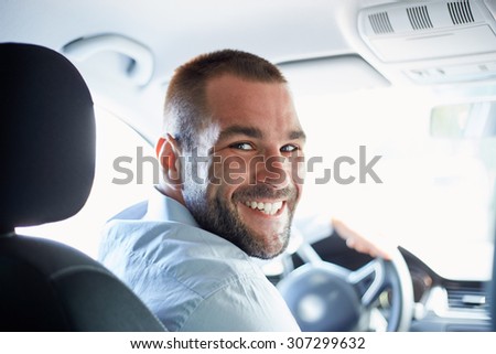 Happy man sitting in a car and looking back