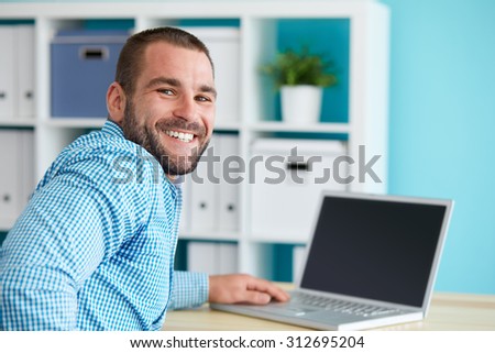 Happy businessman working in modern office on computer
