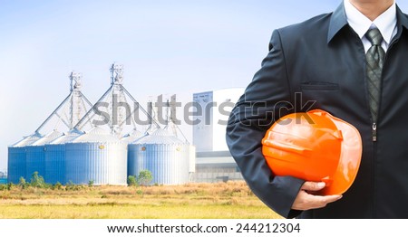 Worker holding a helmet with background of factory exterior