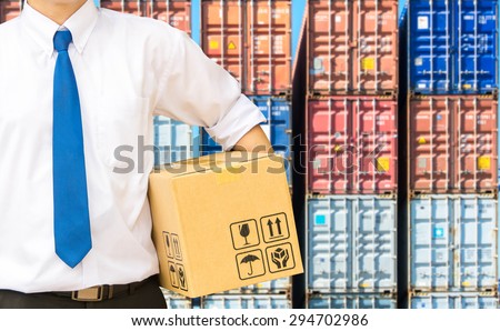 Businessman holding a package parcel on the containers background of a logistic port.