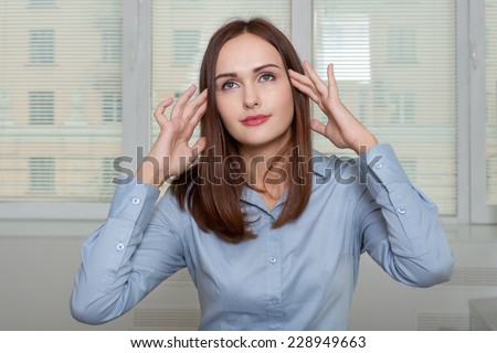 Woman in office holds hands behind his head, as she had a headache