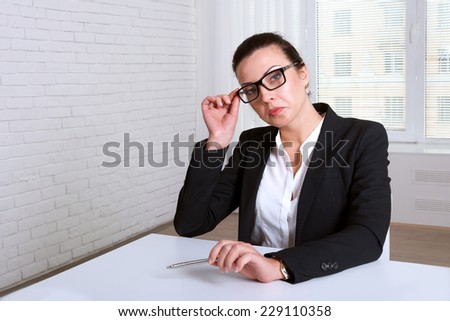 Woman in suit looking disdainfully lifting eye glasses