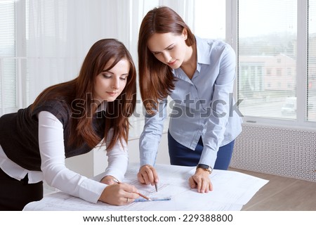 Two female architects studying blueprints and make notes
