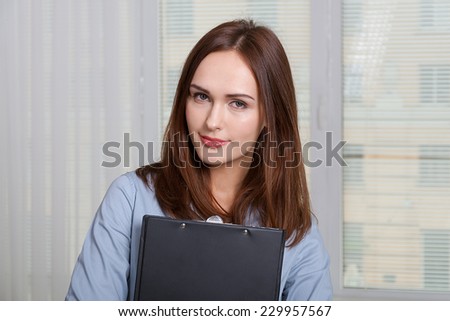 Woman in formal attire holding a folder for documents