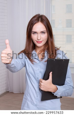 Girl in formal attire holding a folder and gesture shows that everything is OK