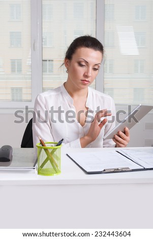Girl in white formal shirt holding a a tablet browsing news