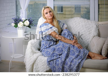 Girl with blond hair sitting on the couch against the window