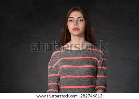 Concept human emotions. Girl shows sadness against the dark background