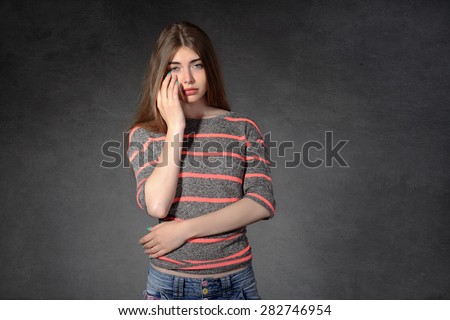 Concept human emotions. Girl shows a grudge against a dark background