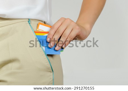 Woman pulls out of her pocket a set of different plastic cards against a light background