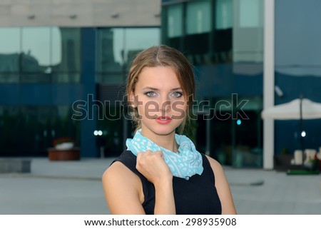 Business woman dressed in a blouse and a scarf against the background of an office building