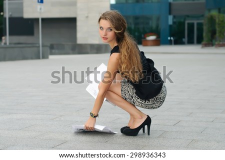 Women fell to the ground documents and she sat down to pick them up