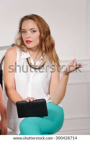 Woman in a clothing store showing her purse in confused against a light background