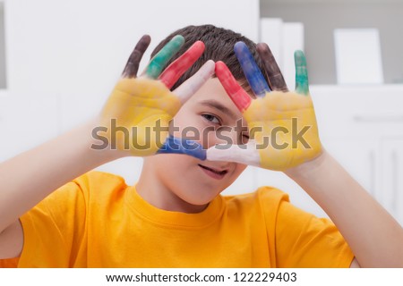 Little boy making funny face with his colored hands