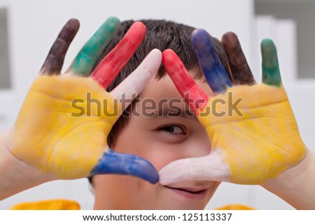Happy boy making funny face with his colored hands