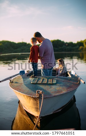 Happy family fishing on boat in summertime. Father teaches son fishing. Back view. Photo for blog about family travel