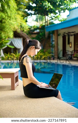 Girl with Laptop by the pool, working on vacation with mobility concept