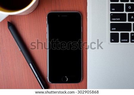 Mobile phone and laptop and a digital pen on a wooden pattern table surface top view