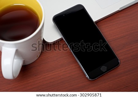 Coffee work table with mobile phone and laptop on a wooden pattern table surface top view, mug