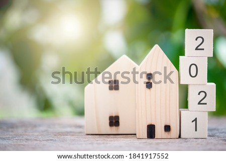 Wooden house model with wooden block number 2021 and copy space using as background concept to save money buying house, new year property, business, real estate and property concept.