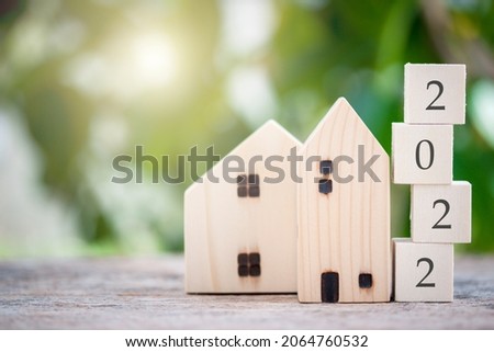 Wooden house model with wooden block number 2022 and copy space using as background concept to save money buying house, new year property, business, real estate and property concept.