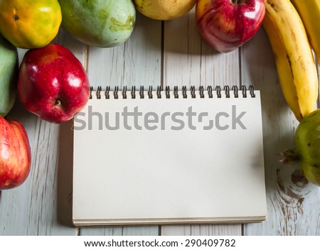 notebook for recipes with fresh fruits on wooden background