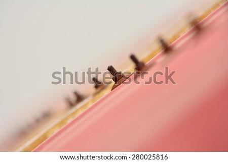 Row of rust screws in the red roof which is focus close up
