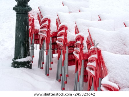 Red chairs stacked in the snow . Concept showing how the snow or bad weather can stop an event