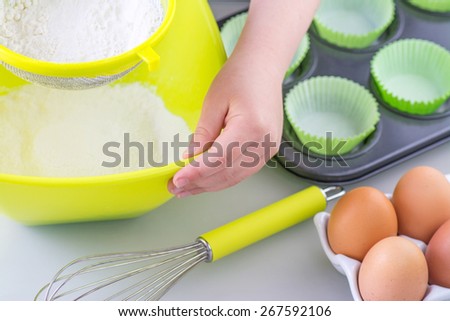 Child sieving flour into a bowl in preparation for  cooking cake, room for text