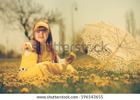 little girl enjoying the sunny spring day in fields flowers. vintage-look/ girl in field of flowers